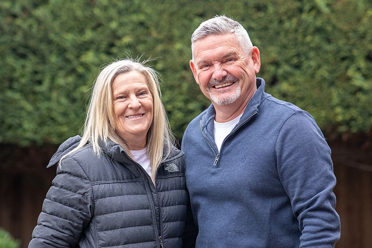 Couple standing outside in front of trees